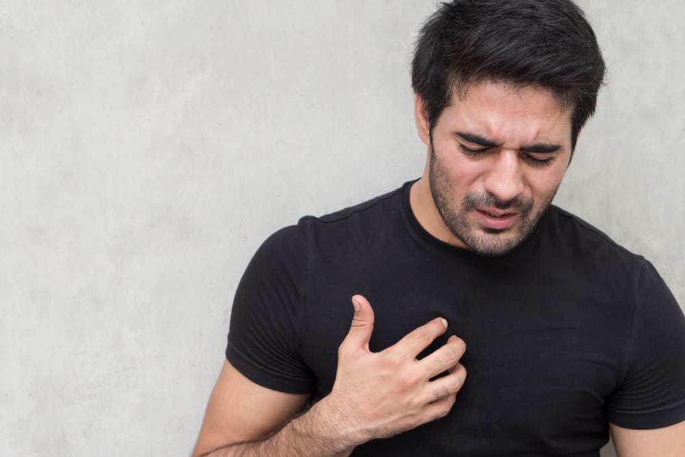 A young man is touching his chest in pain due to acid reflux