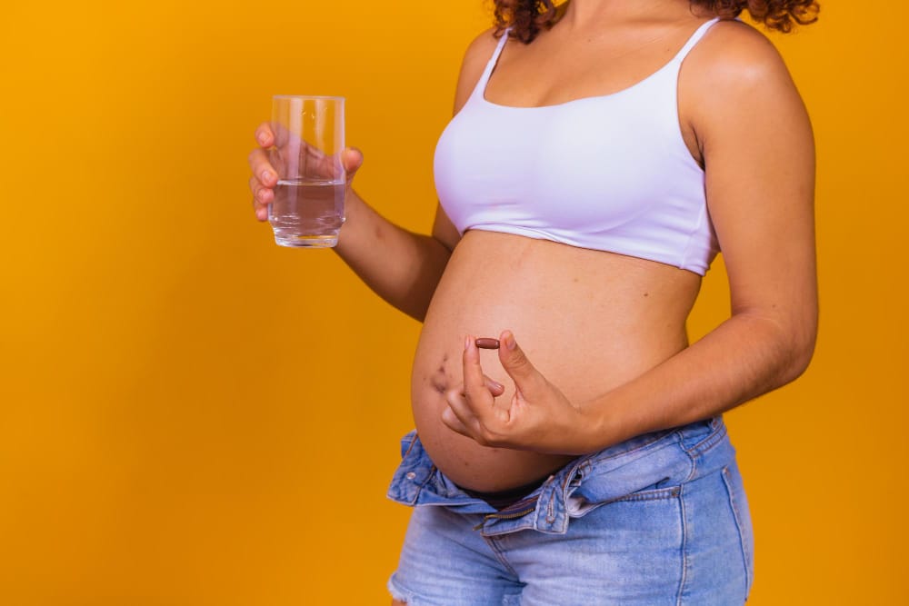 A pregnant woman is about to take her prenatal vitamins