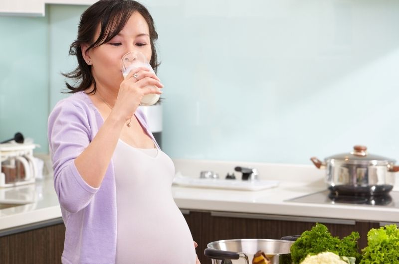 A pregnant woman is drinking milk with honey to help ease her acid reflux