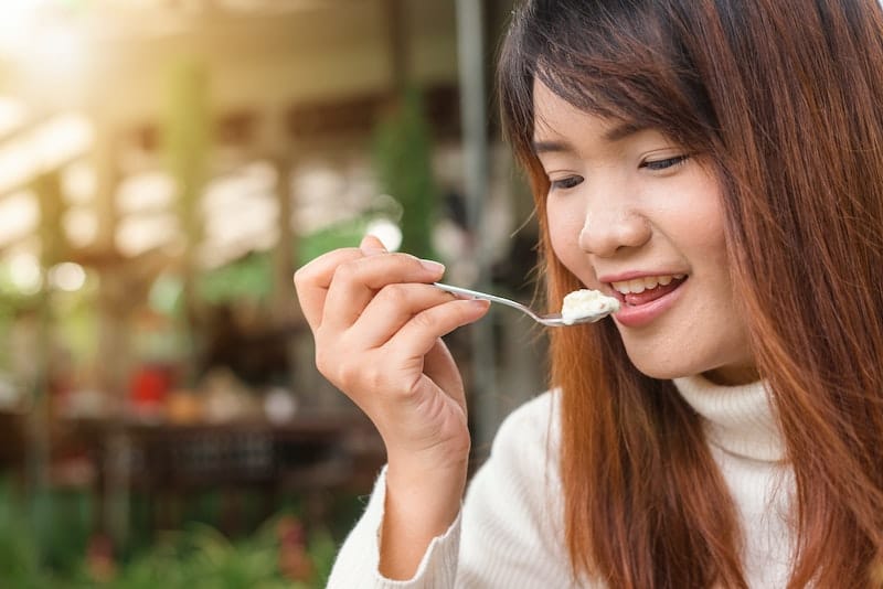 A woman is eating yogurt as part of her regular diet, to help combat her BV.