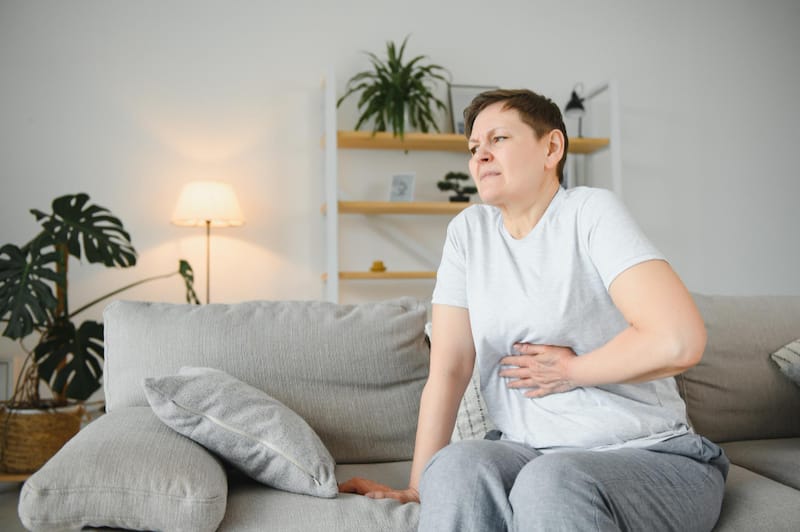 A woman is experiencing pain from bloating, possibly caused by her intake of sorbitol earlier.