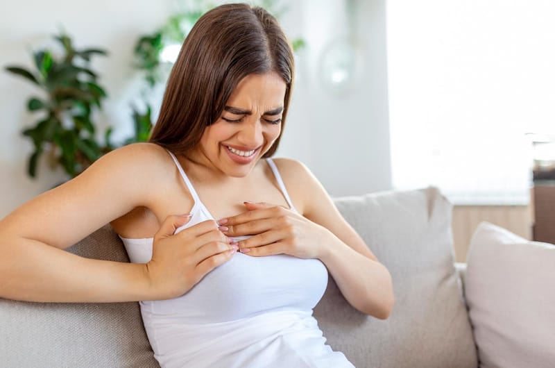 A woman is clenching her right breast as she's noticing an icy cold feeling and pain discomfort 