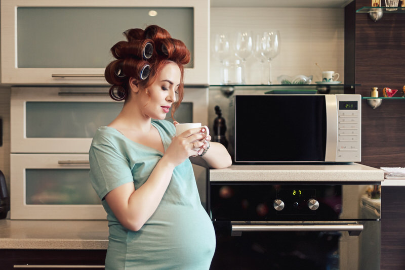 A pregnant woman is having her morning cup of coffee to get her day startred