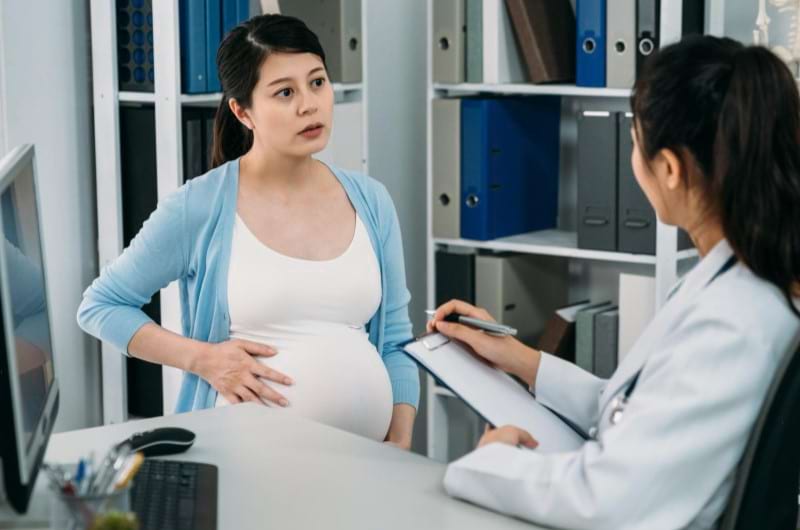 A pregnant woman discussing self-care strategies with her doctor to manage her mental health issues.